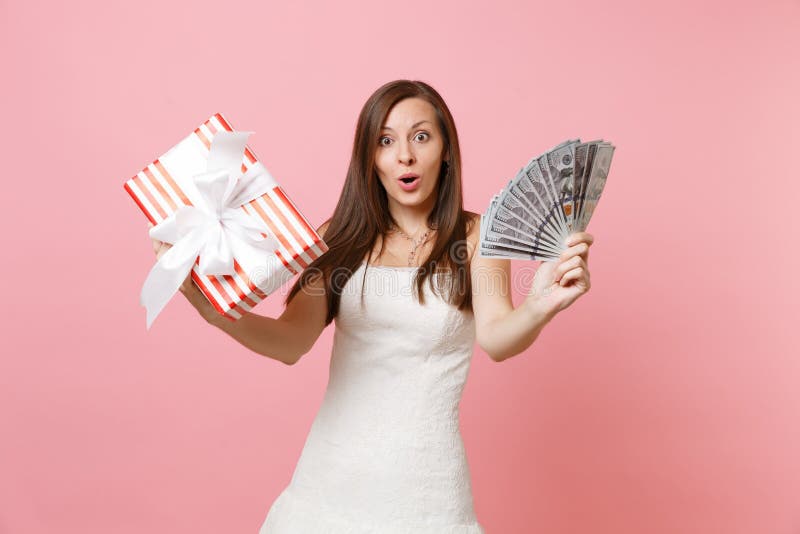 Mujer chocada Amazed de la novia en el vestido que se casa blanco que lleva a cabo porciones del paquete de dólares, dinero del e foto de archivo libre de regalías Mujer chocada Amazed de la novia en el vestido que se casa blanco que lleva a cabo porciones del paquete de dólares, dinero del e foto de archivo libre de regalías
