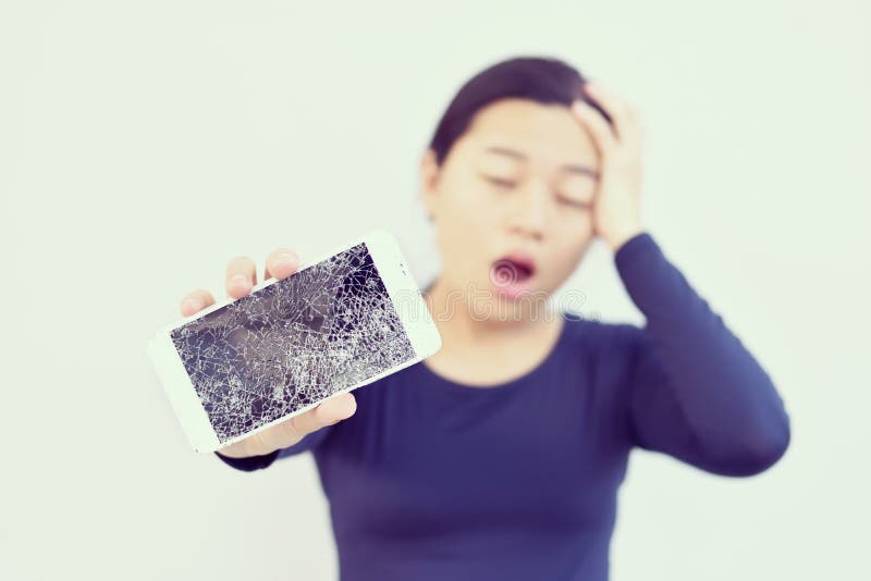 Mujer chocada con un teléfono quebrado en su mano.