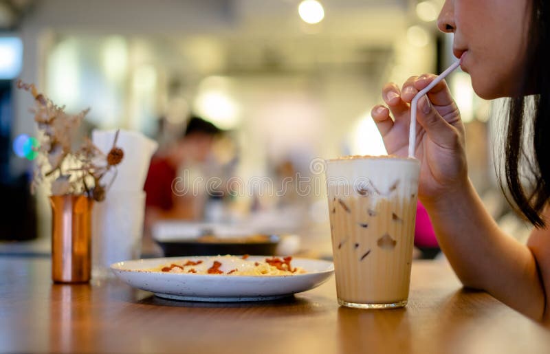 Mujer chupa café con leche, Hermosa joven que disfruta café con leche en café. imágenes de archivo libres de regalías