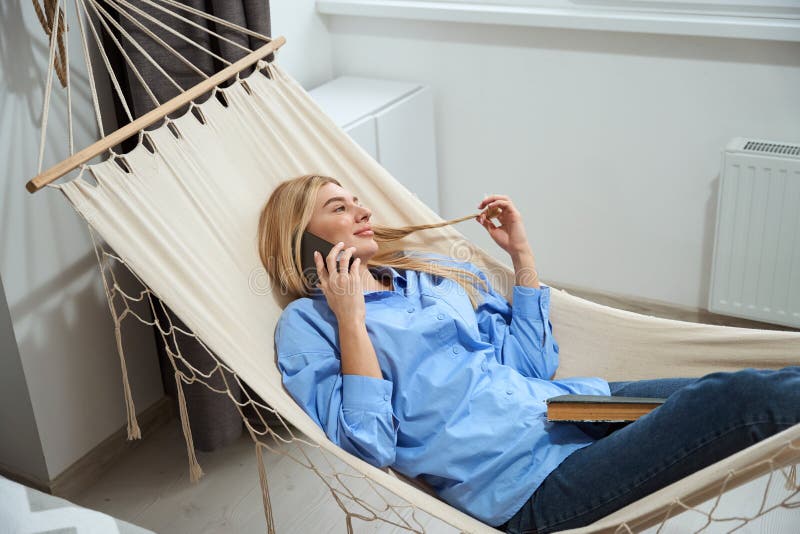 Mujer complacida llamando al teléfono móvil durante el descanso de la tarde fotos de archivo