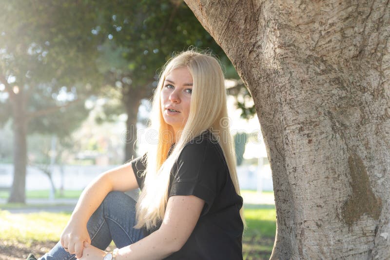 Mujer con bronce relajándose bajo el árbol en el parque fotos de archivo