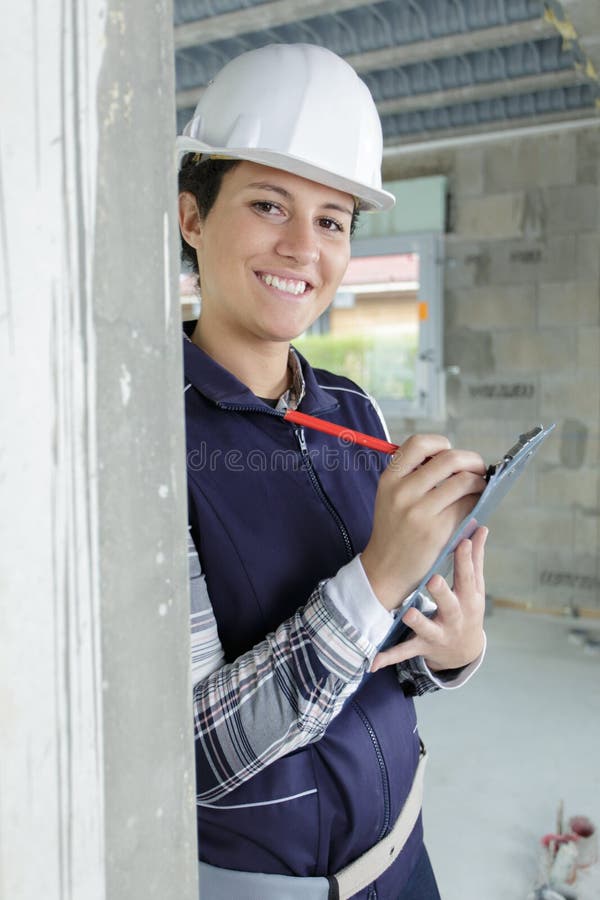 Mujer con casco y portapapeles dentro del sitio de construcción fotos de archivo