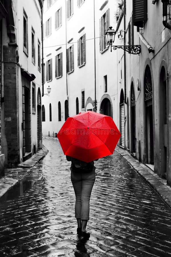 Mujer con el paraguas rojo en la calle retra en la ciudad vieja Viento y lluvia