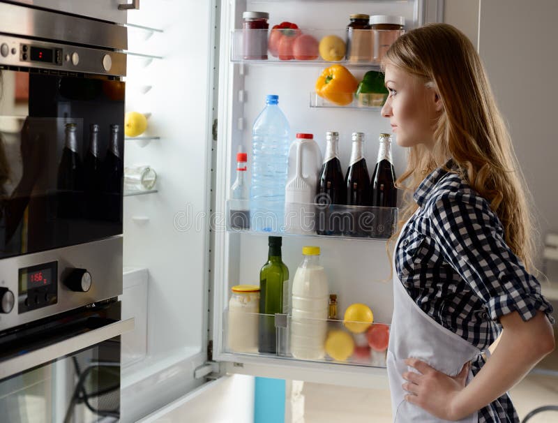 Mujer con el refrigerador abierto fotografía de archivo Mujer con el refrigerador abierto fotografía de archivo