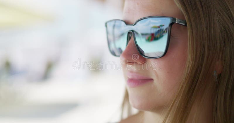 Mujer con gafas de sol con reflejo en la playa almacen de metraje de vídeo