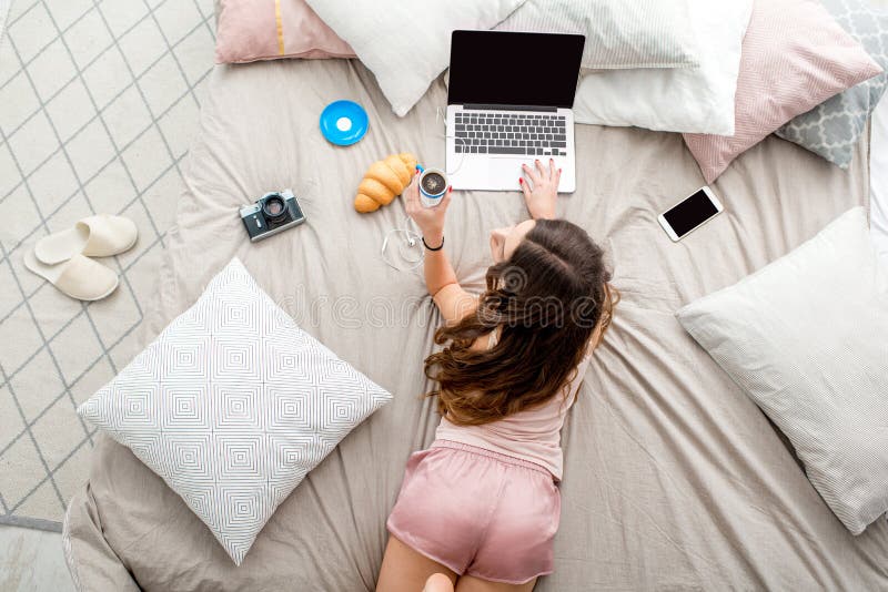 Mujer con la computadora portátil en la cama fotos de archivo libres de regalías Mujer con la computadora portátil en la cama fotos de archivo libres de regalías