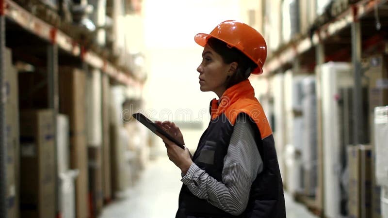 Mujer con la tableta que trabaja en almacenamiento