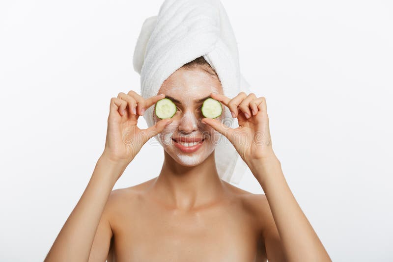 Mujer con las rebanadas faciales de la máscara y del pepino en sus manos en el fondo blanco fotografía de archivo libre de regalías Mujer con las rebanadas faciales de la máscara y del pepino en sus manos en el fondo blanco fotografía de archivo libre de regalías
