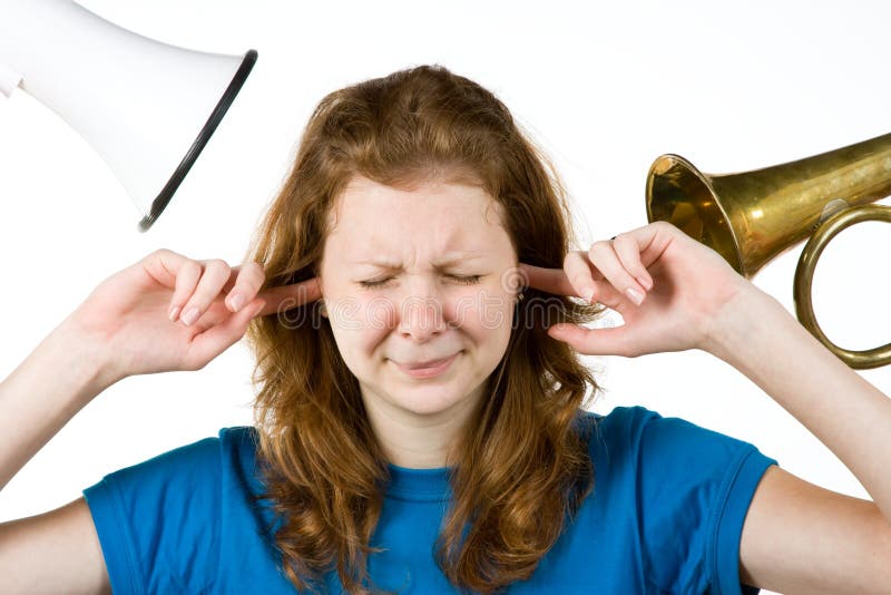 A woman with her fingers in her ears because of the loud noise. A woman with her fingers in her ears because of the loud noise.