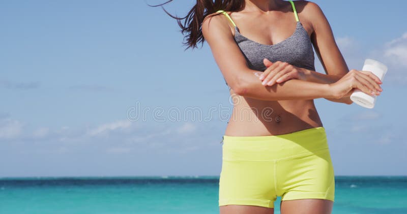 Mujer con pantalla solar. chica poniendo un bloque solar en la playa sosteniendo una botella de bronceado blanco. hermosa joven di almacen de metraje de vídeo