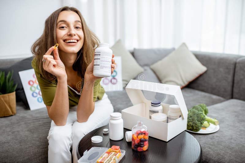 Portrait of a young smiling woman taking nutritional supplements at home. Concept of biohacking and preventive medicine. Portrait of a young smiling woman taking nutritional supplements at home. Concept of biohacking and preventive medicine