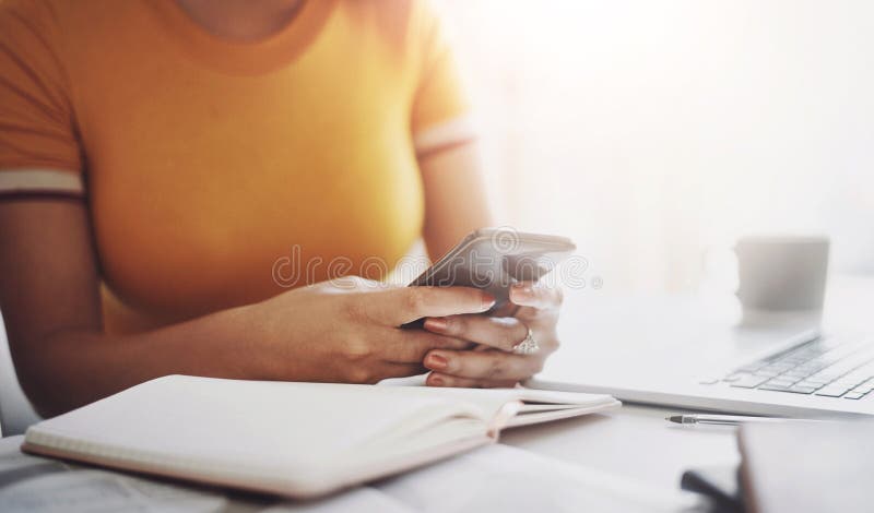 Mujer con un smartphone y una laptop cerca de su escritorio en la oficina. conectividad de medios sociales o de comunicación, o fotos de archivo libres de regalías
