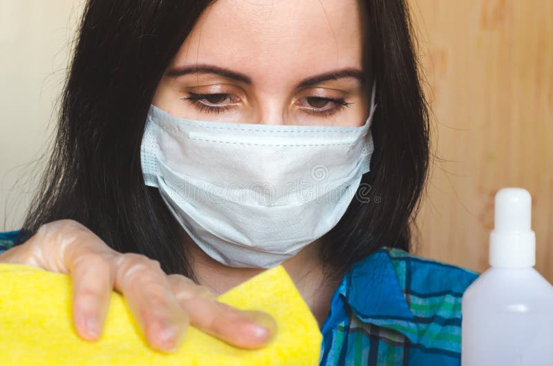 Mujer con una máscara de protección contra virus médicos con un trapo y un agente antibacteriano limpia su casa. retrato de cierre foto de archivo libre de regalías