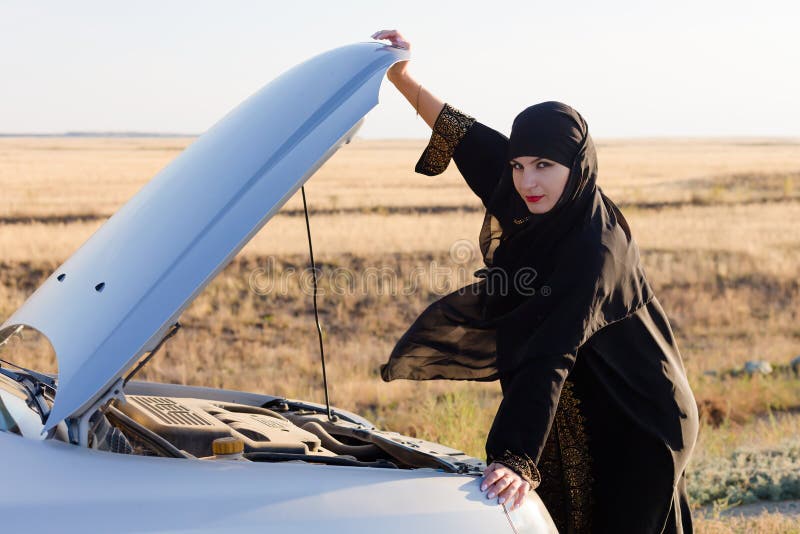 Mujer conductor mirando motor de coche roto mientras sostiene capucha imagenes de archivo