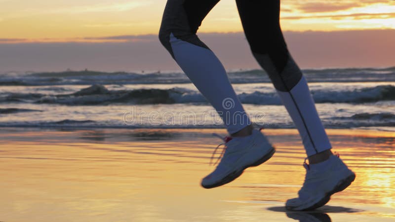 Mujer corriendo en la playa del atardecer Calzado deportivo, huellas de arena húmeda