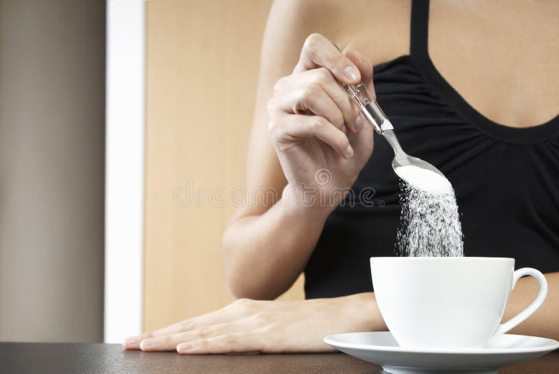Mujer cosechada que vierte a Sugar In Tea Cup