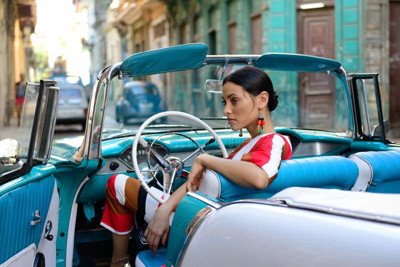 HAVANA, CUBA - 11 DECEMBER 2016: The beautiful Cuban woman is getting the classical American car off in the centre of old Havana on Cuba. HAVANA, CUBA - 11 DECEMBER 2016: The beautiful Cuban woman is getting the classical American car off in the centre of old Havana on Cuba