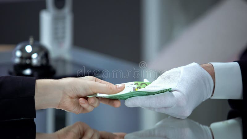 Mujer dando recepcionista con billetes en euros de guante blanco, pagando por el servicio fotos de archivo libres de regalías Mujer dando recepcionista con billetes en euros de guante blanco, pagando por el servicio fotos de archivo libres de regalías