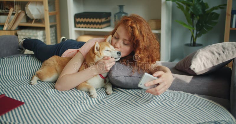 Mujer de amor que besa el perrito lindo y tomar el selfie con smartphone en el sofá