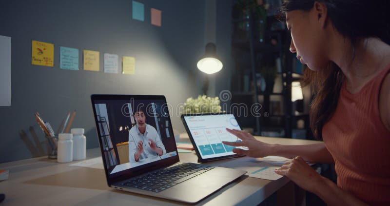 Mujer de asia que usa laptop ver grafo en la mesa conversar con colegas sobre el trabajo en videollamadas mientras trabaja desde c metrajes