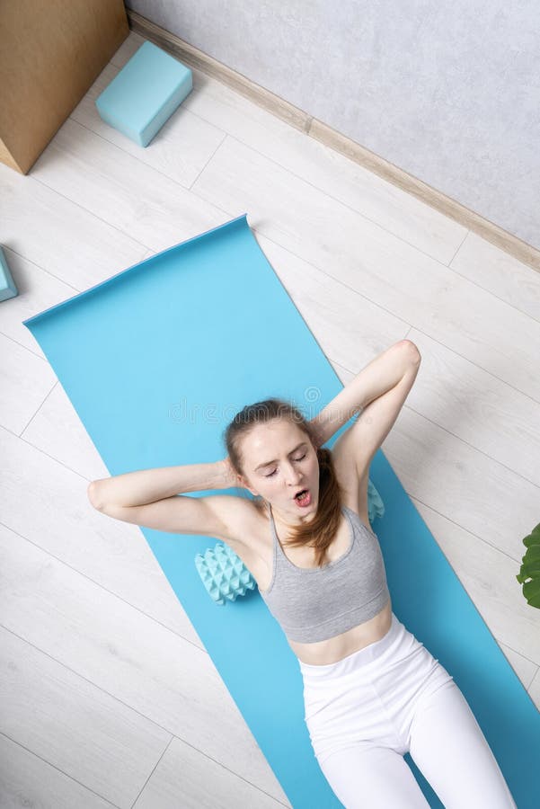 Mujer de fitness con rodillo de espuma por debajo de la espalda. vista superior. hermosa mujer caucásica usa rodillo para fisioter fotos de archivo libres de regalías