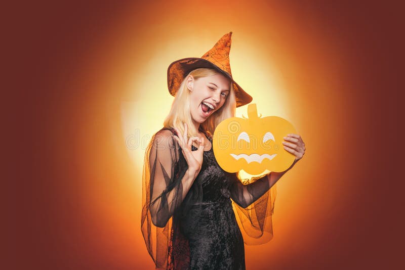 Mujer de la belleza que presenta con el sombrero de la calabaza y de Halloween Retrato del primer de la encantadora de hadas rubi foto de archivo Mujer de la belleza que presenta con el sombrero de la calabaza y de Halloween Retrato del primer de la encantadora de hadas rubi foto de archivo