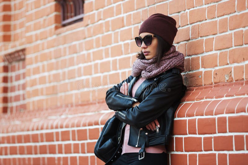 Mujer de la moda de los jóvenes en la chaqueta de cuero negra que se inclina en la pared de ladrillo fotos de archivo libres de regalías Mujer de la moda de los jóvenes en la chaqueta de cuero negra que se inclina en la pared de ladrillo fotos de archivo libres de regalías