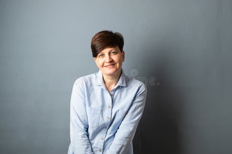 Mujer de mediana edad que plantea la situaci?n cerca de la pared Retrato de la mujer en un fondo gris Copie el espacio imagen de archivo libre de regalías Mujer de mediana edad que plantea la situaci?n cerca de la pared Retrato de la mujer en un fondo gris Copie el espacio imagen de archivo libre de regalías