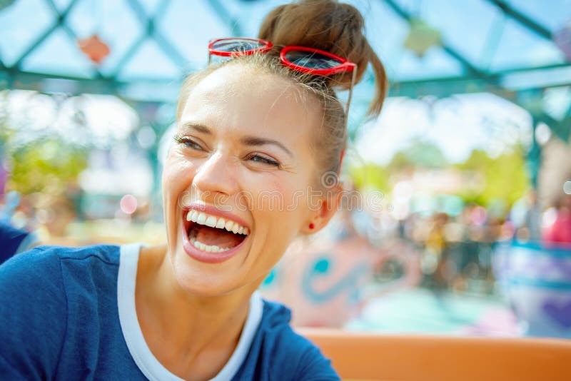 Mujer de moda sonriente en parque de atracciones que disfruta de paseo foto de archivo Mujer de moda sonriente en parque de atracciones que disfruta de paseo foto de archivo