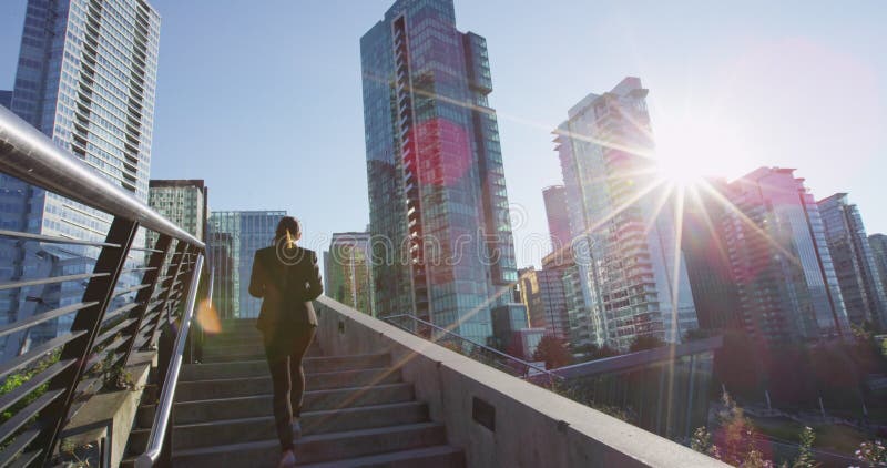Mujer de negocios caminando por las escaleras afuera con smartphone y café en vancouver almacen de metraje de vídeo