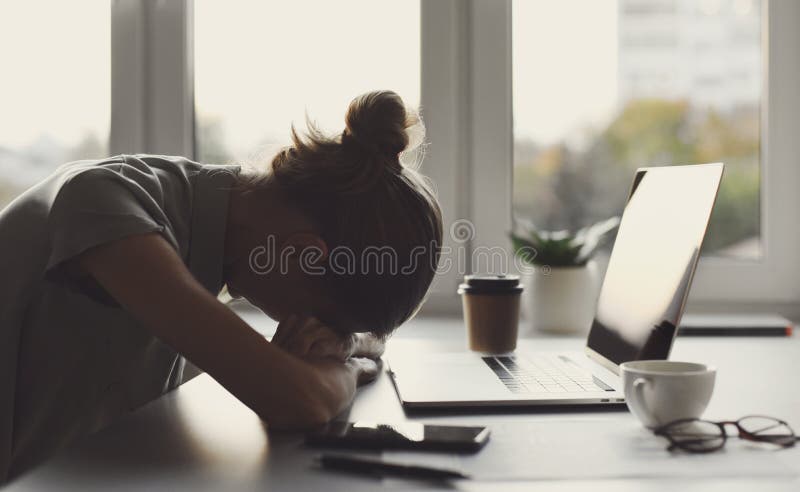 Mujer de negocios cansada durmiendo en la mesa en la oficina. muchacha exhausta joven con exceso de trabajo que trabaja desde casa imagenes de archivo
