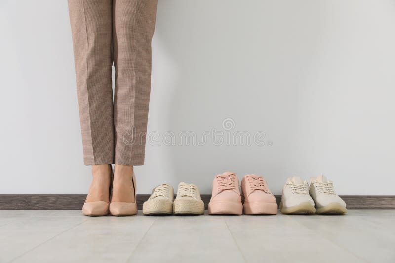 Mujer De Negocios Con Zapatos Tacón Alto Cerca De Cómodas Zapatillas De Deporte En El Interior de archivo - de espacio, deporte: 254175678