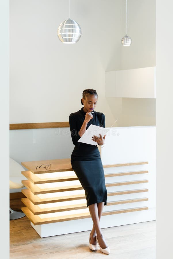 Mujer De Negocios Elegante Severa Que El Vestido Negro Y Los Zapatos Beige La Oficina Ligera Que Mira Su Orden Del Día, Imagen de archivo - Imagen de programa, hermoso: