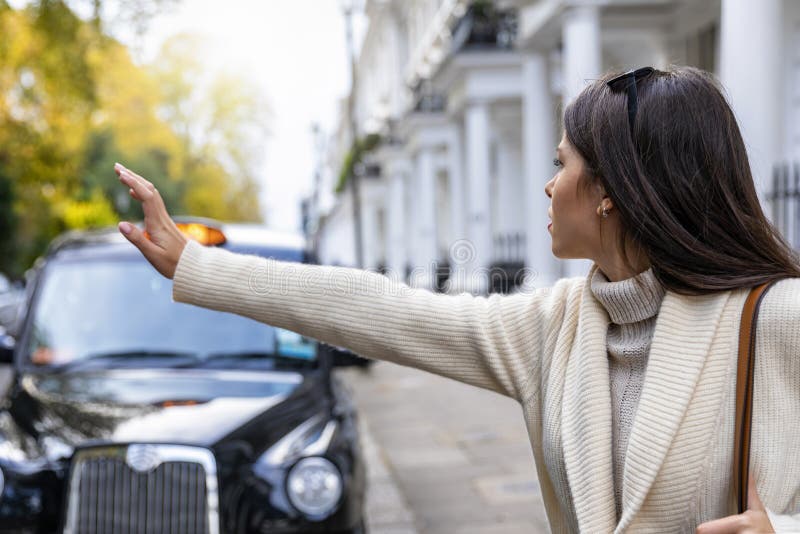 Mujer de negocios en Londres que graniza para un taxi negro imagen de archivo libre de regalías Mujer de negocios en Londres que graniza para un taxi negro imagen de archivo libre de regalías