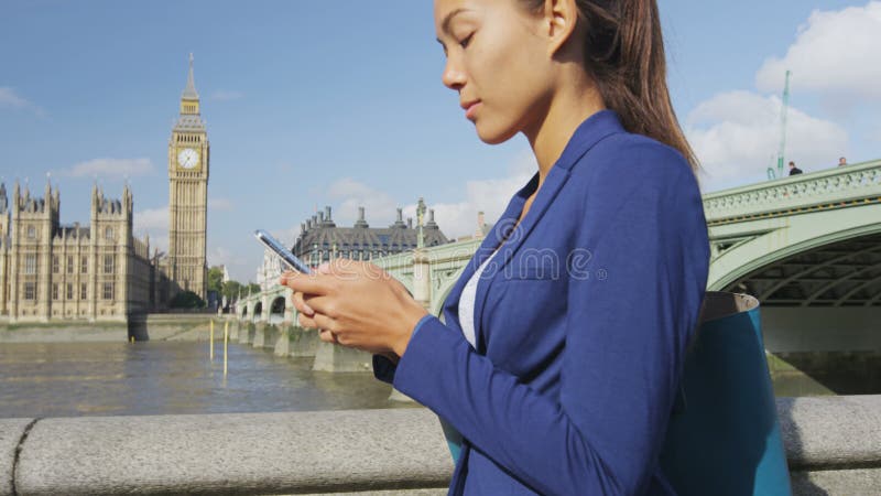 Mujer de negocios envía mensajes de texto desde una aplicación para smartphone en londres england