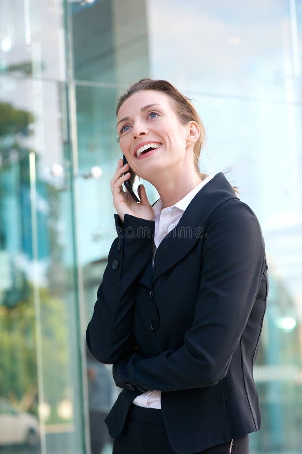 Mujer de negocios feliz que camina y que habla en el teléfono móvil foto de archivo libre de regalías Mujer de negocios feliz que camina y que habla en el teléfono móvil foto de archivo libre de regalías