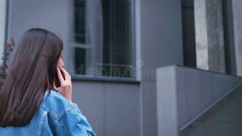 Mujer de negocios de lado trasero caminando en una corporación de negocios o centro comercial hablar teléfono móvil comunicarse en