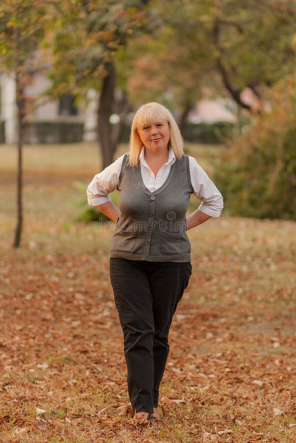 Mujer De Negocios Mayor Que Camina En El Parque Del Otoño Una