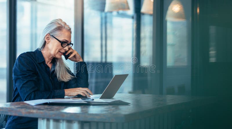 Mujer de negocios mayor que habla en el teléfono celular imagen de archivo Mujer de negocios mayor que habla en el teléfono celular imagen de archivo
