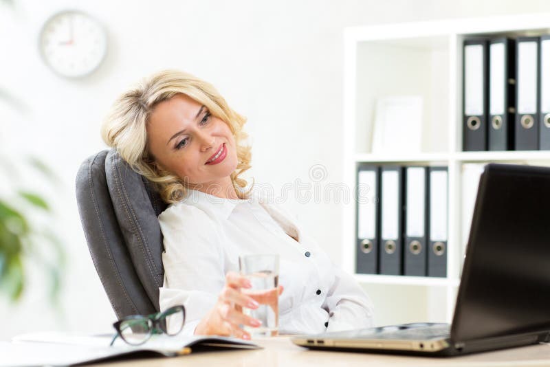 Mujer de negocios mayor que se relaja en el trabajo en oficina fotos de archivo libres de regalías Mujer de negocios mayor que se relaja en el trabajo en oficina fotos de archivo libres de regalías
