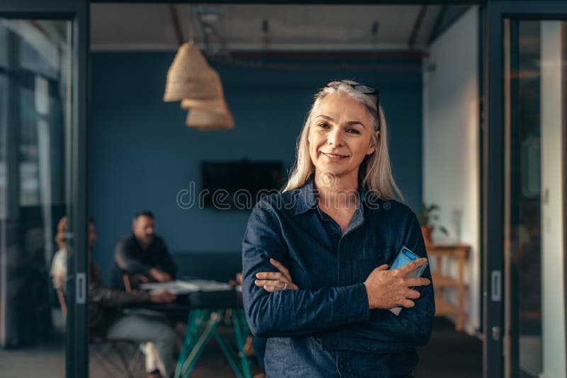 Mujer de negocios mayor sonriente en la oficina foto de archivo libre de regalías Mujer de negocios mayor sonriente en la oficina foto de archivo libre de regalías