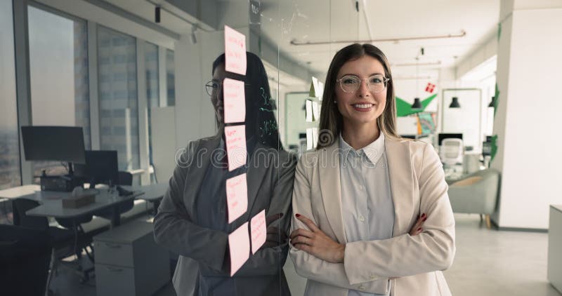 Mujer de negocios positiva con elegantes gafas de pie en el tablero de escrúpulos almacen de metraje de vídeo