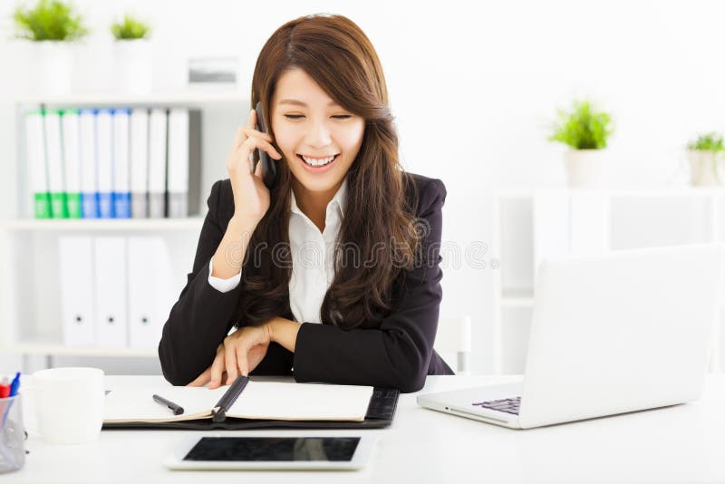 Mujer de negocios que habla en el teléfono en oficina imagen de archivo Mujer de negocios que habla en el teléfono en oficina imagen de archivo