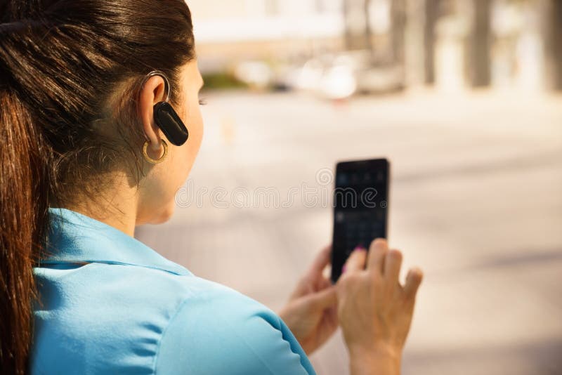 Mujer de negocios que hace una llamada de teléfono con el dispositivo del bluetooth fotografía de archivo libre de regalías Mujer de negocios que hace una llamada de teléfono con el dispositivo del bluetooth fotografía de archivo libre de regalías