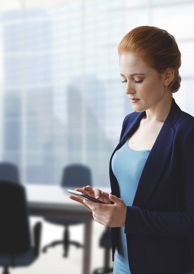Mujer de negocios que usa un teléfono contra fondo de la oficina imagen de archivo Mujer de negocios que usa un teléfono contra fondo de la oficina imagen de archivo