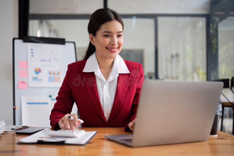 Mujer de negocios que utiliza una calculadora para hacer matemáticas en un escritorio de madera en el despacho y en el trabajo de fotos de archivo