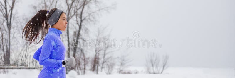 Mujer de reloj inteligente que corre en invierno con frío que trota afuera usando ropa a prueba de viento con guantes, banda de c