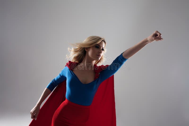 Mujer del super héroe Blonde joven y hermoso en la imagen del superheroine en el crecimiento rojo del cabo fotografía de archivo libre de regalías Mujer del super héroe Blonde joven y hermoso en la imagen del superheroine en el crecimiento rojo del cabo fotografía de archivo libre de regalías