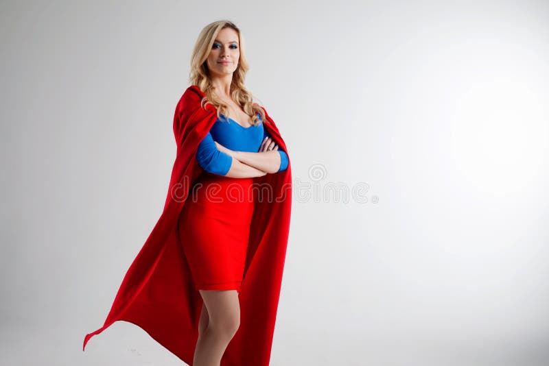 Mujer del super héroe Blonde joven y hermoso en la imagen del superheroine en el crecimiento rojo del cabo foto de archivo libre de regalías Mujer del super héroe Blonde joven y hermoso en la imagen del superheroine en el crecimiento rojo del cabo foto de archivo libre de regalías