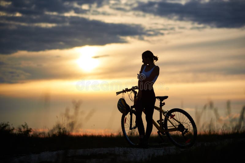 Mujer delgada, deportiva que coloca la bici cercana y la presentación imagen de archivo Mujer delgada, deportiva que coloca la bici cercana y la presentación imagen de archivo